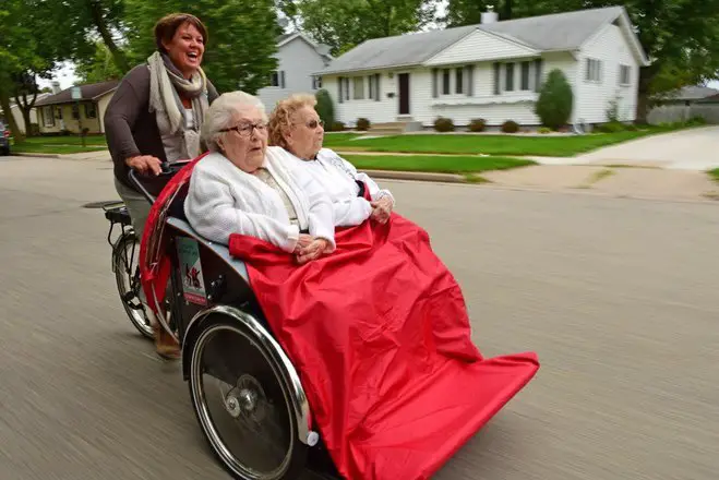 Seniors in a wheelchair pushed by a bike