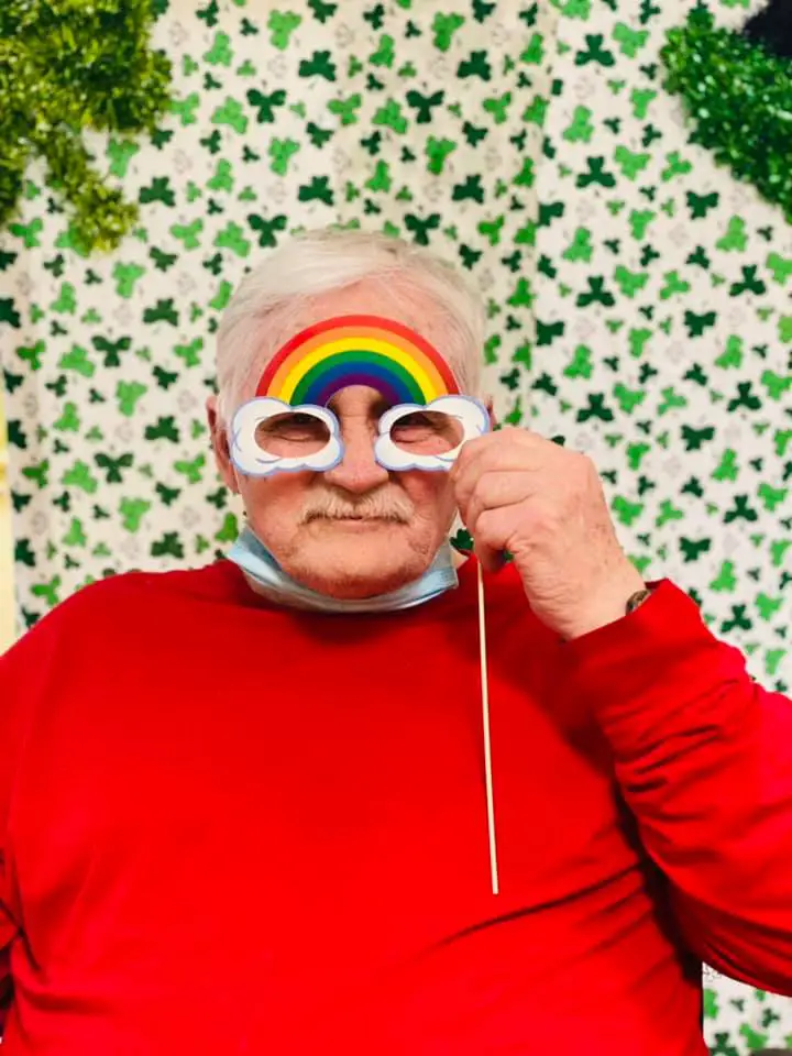 elderly man holding a lucky rainbow mask 