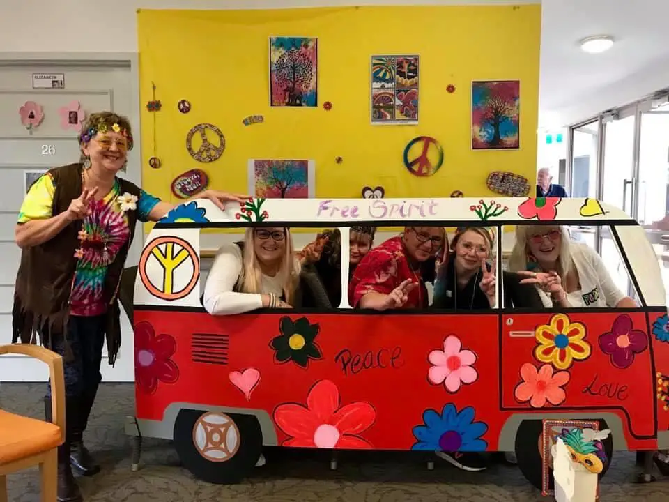 women posing with their 1960s Hippy Day themed van