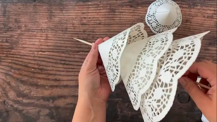 person poking the paper doilies to the skewer