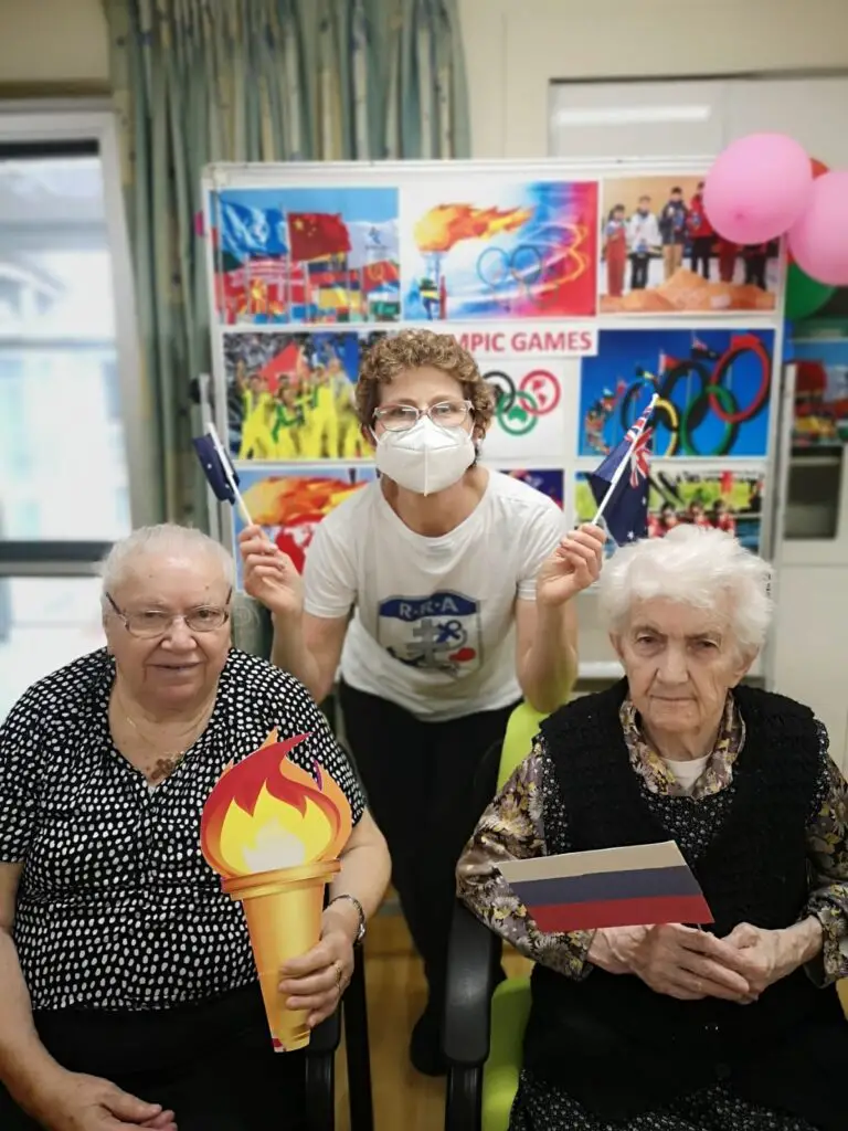 a staff and two seniors celebrating Olympics in senior care facility