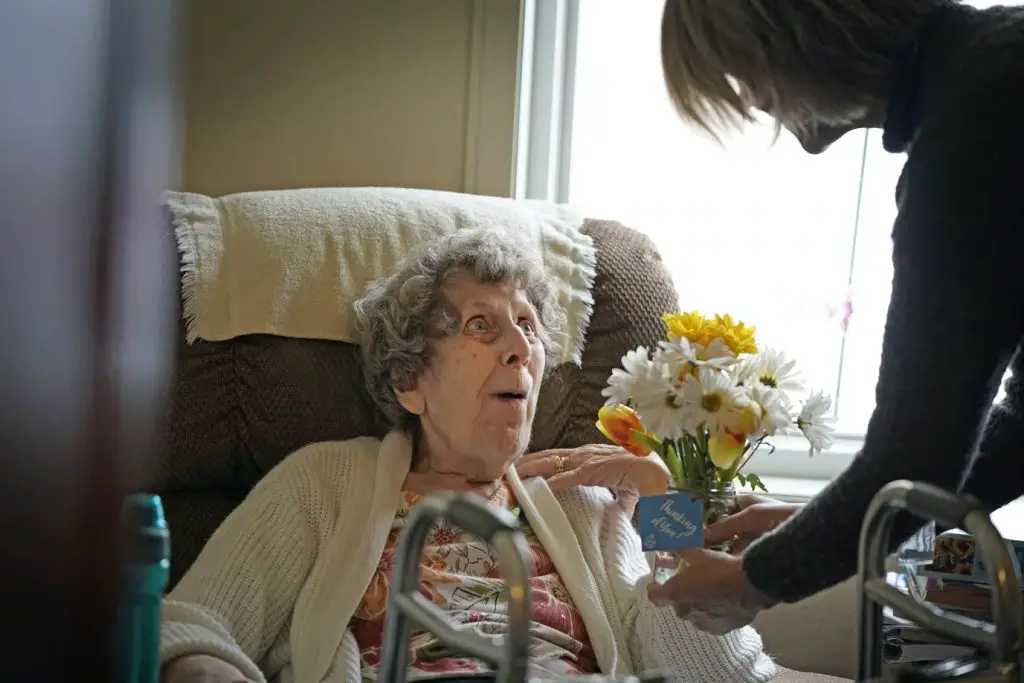 woman handing an elderly woman some flowers