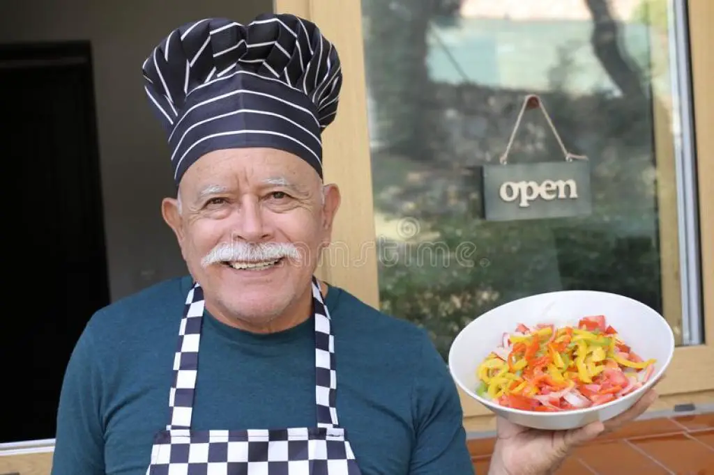 Elderly person wearing an apron and chef hat