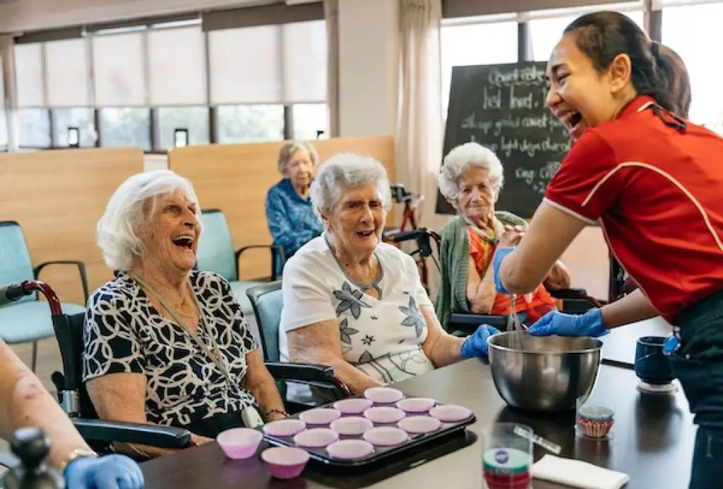 aged care staff making cupcake in front of seniors in aged care