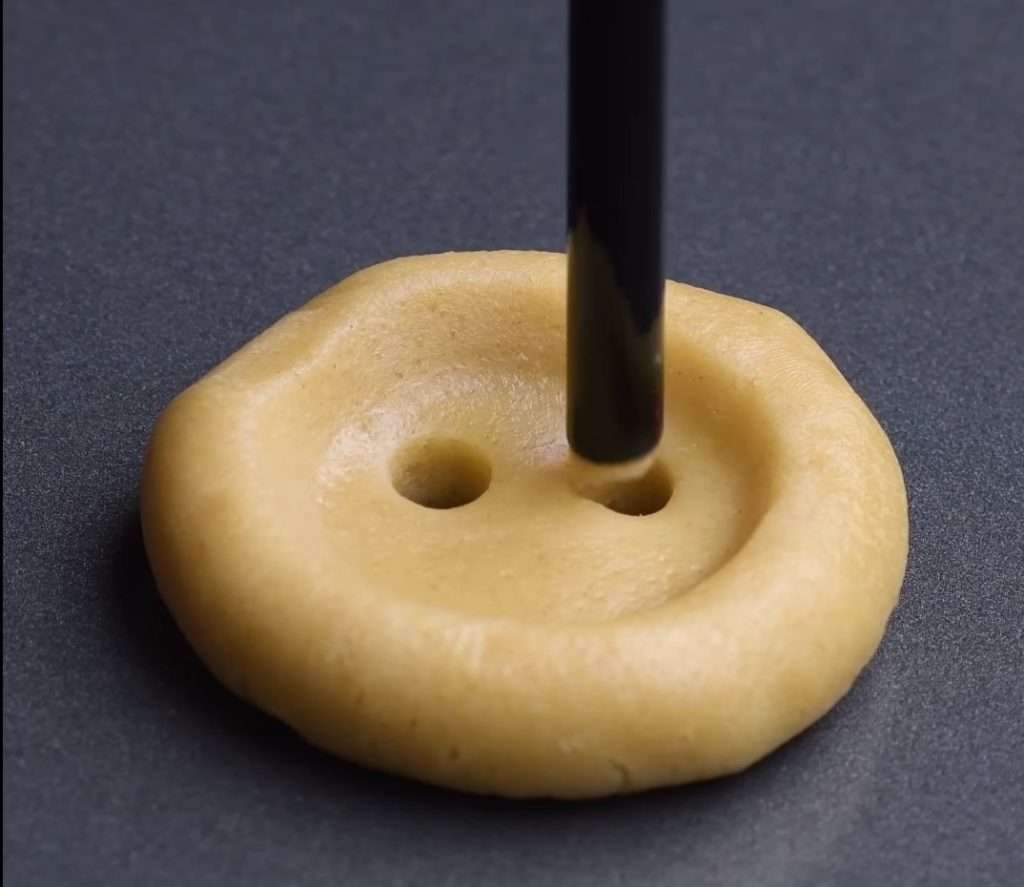 For a creative cookie baking, a bottle cap and a straw is used to pattern the dough like a button