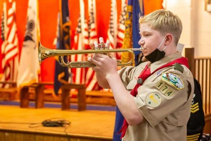 Boy scout playing instrument in a veterans day ceremony