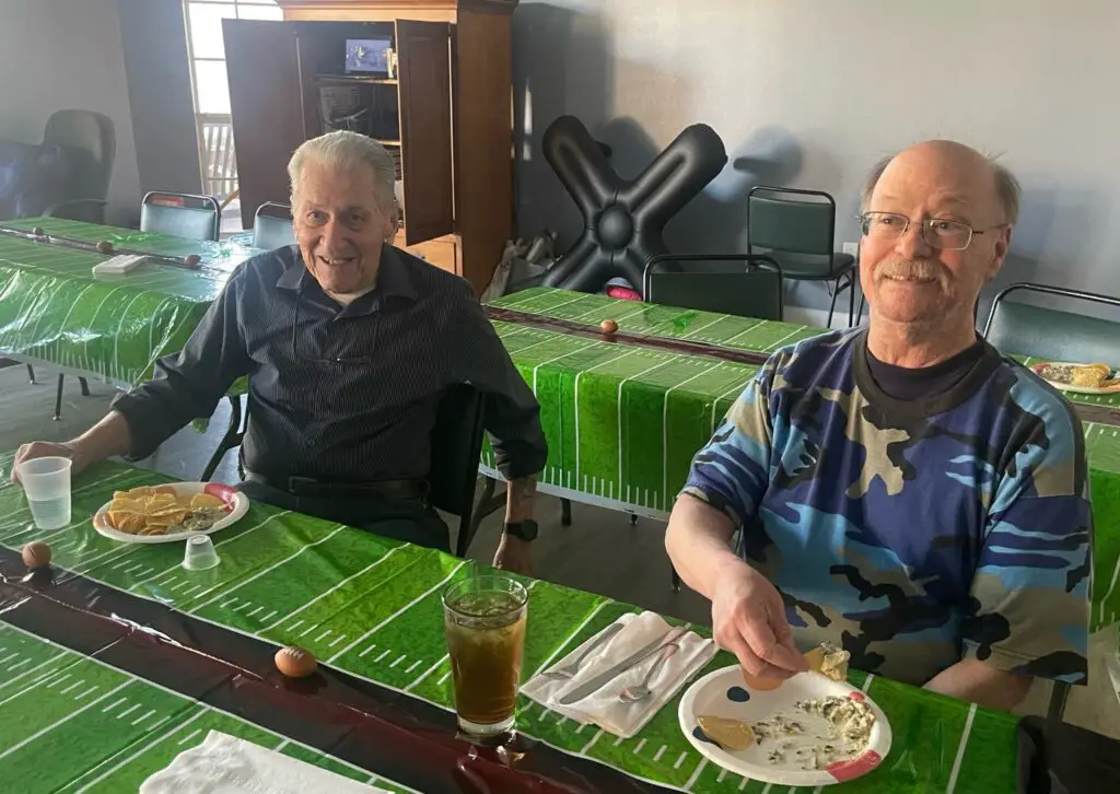 two elderly man eating at a football themed table