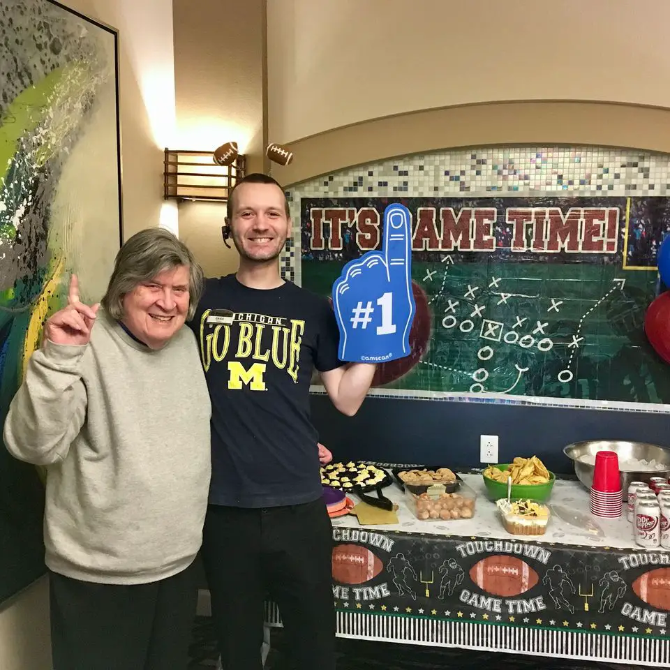 Aged care staff and elderly woman taking picture in a football themed snack table