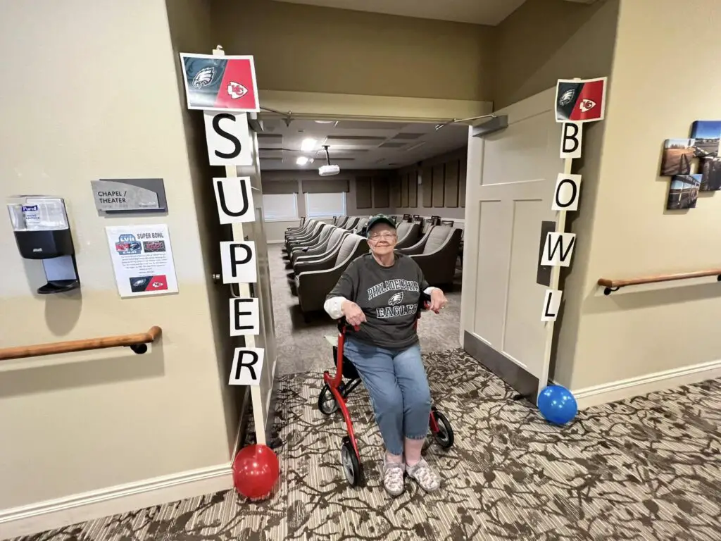 elderly woman in wheelchair taking a picture in super bowl themed decoration