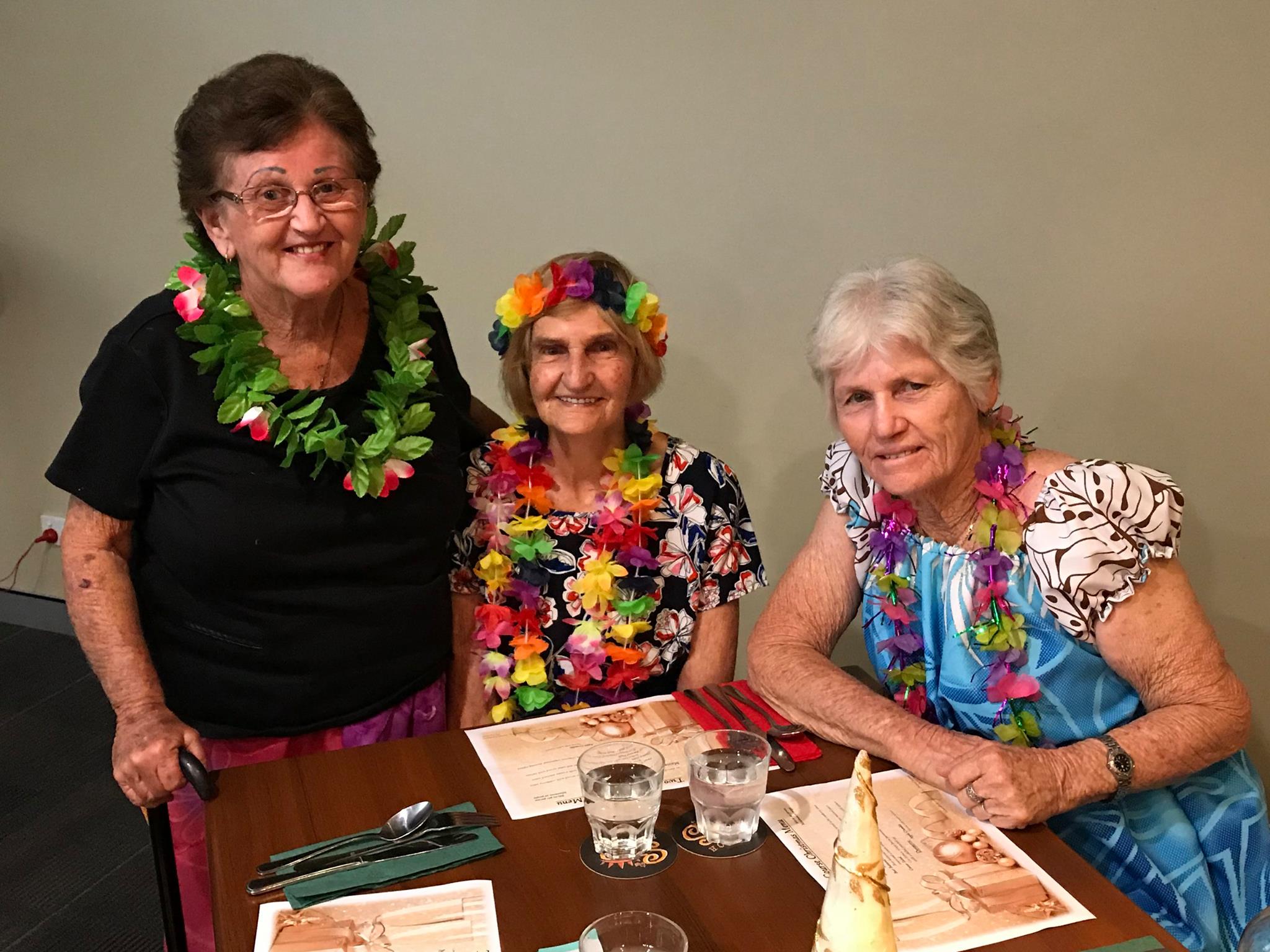 Three elderly lady dressed in Hawaiian themed outfits