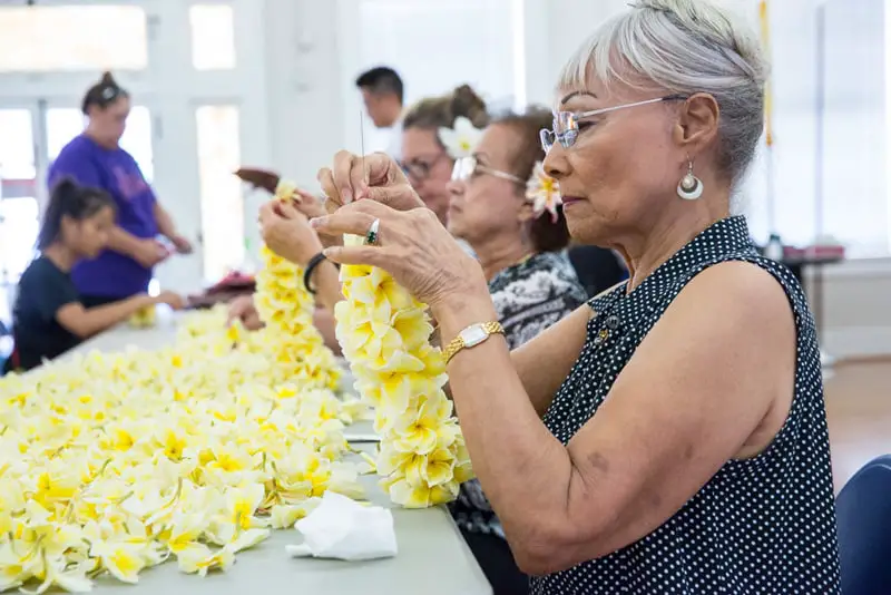 elderly baby boomer making Hawaiian lei