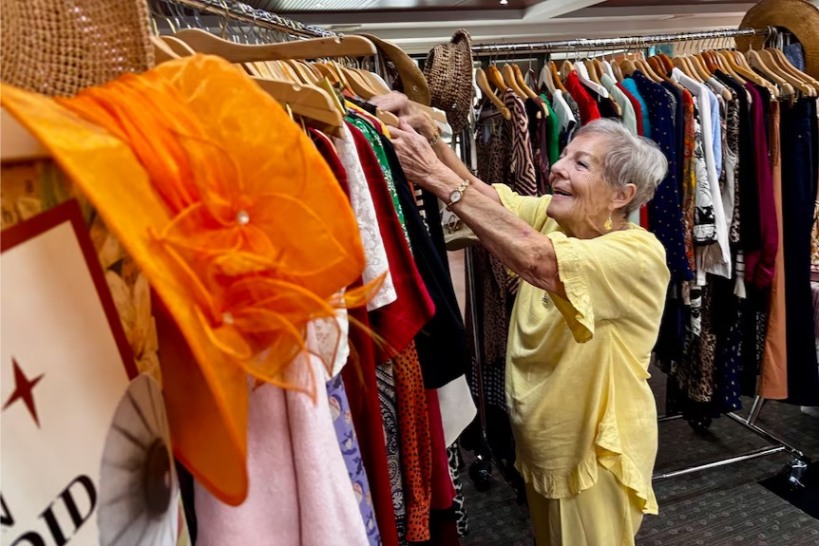 senior woman looking through clothes at a thrift store