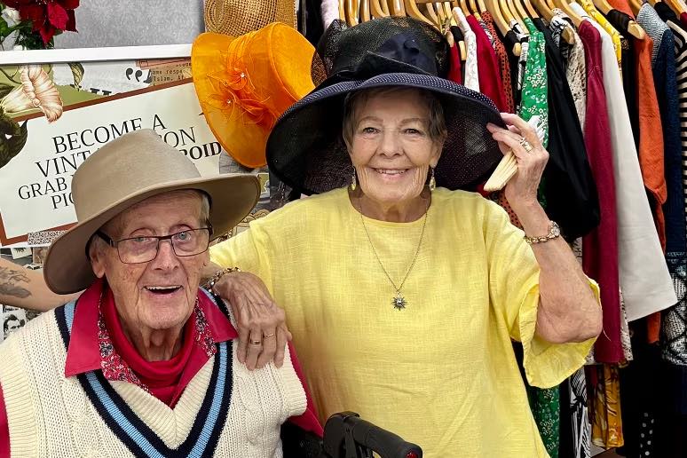 senior citizens trying on hats at a op shop