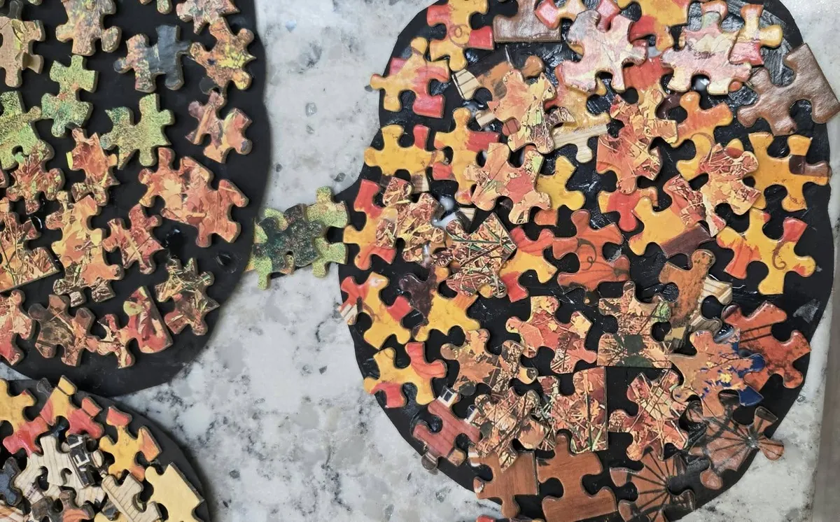 Close-up of a puzzle piece pumpkin with orange, yellow, red and brown jigsaw pieces glued on a black card pumpkin shape